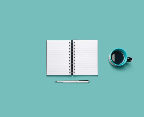 Notebook, pen, and a coffee mug.