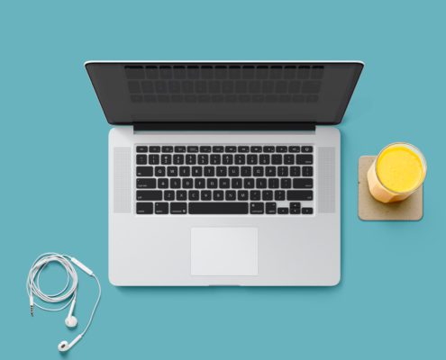 Laptop, headphones, and juice on teal background.