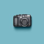 Black camera on a turquoise background.