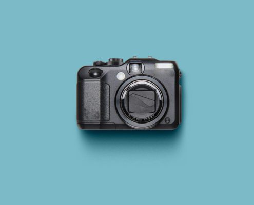 Black camera on a turquoise background.