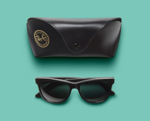 Ray-Ban sunglasses and case on teal background.