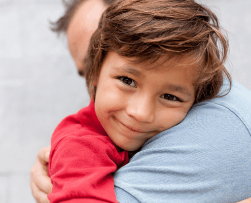 Child smiling while hugging an adult.