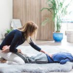 A Woman Helping With Setting the Back of a Person on an Area Rug