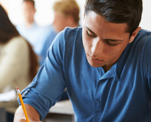 Student writing in a classroom setting.