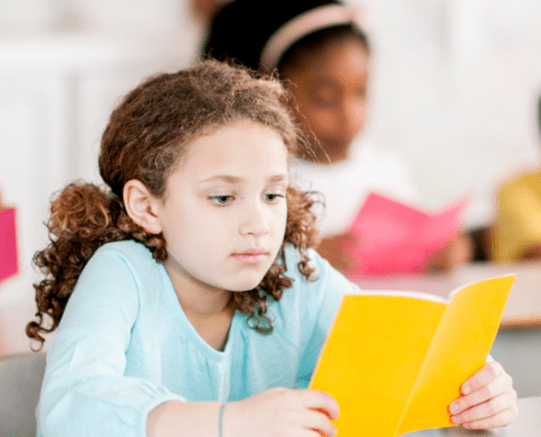 Child reading a yellow book in class.