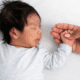 Sleeping newborn holding an adult's hand.