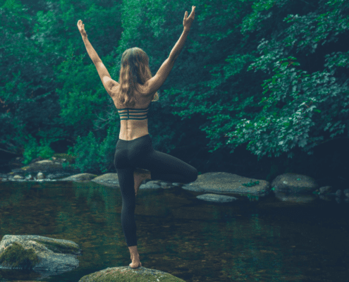 Woman doing yoga pose by a river.