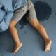 Child wetting bed, lying on blue sheets.
