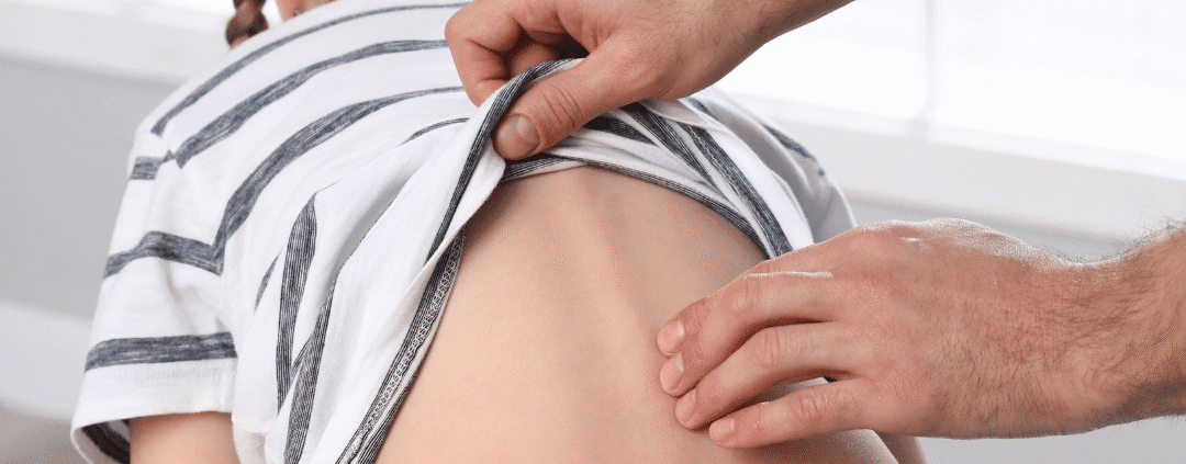 Checking child's back for scoliosis examination.