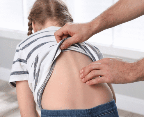 Checking child's back for scoliosis examination.