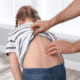 Checking child's back for scoliosis examination.