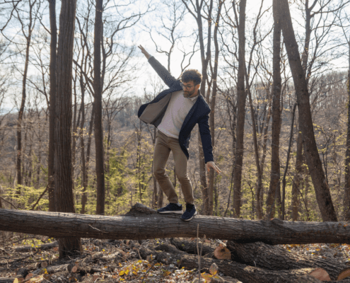 Man balancing on a fallen tree trunk.
