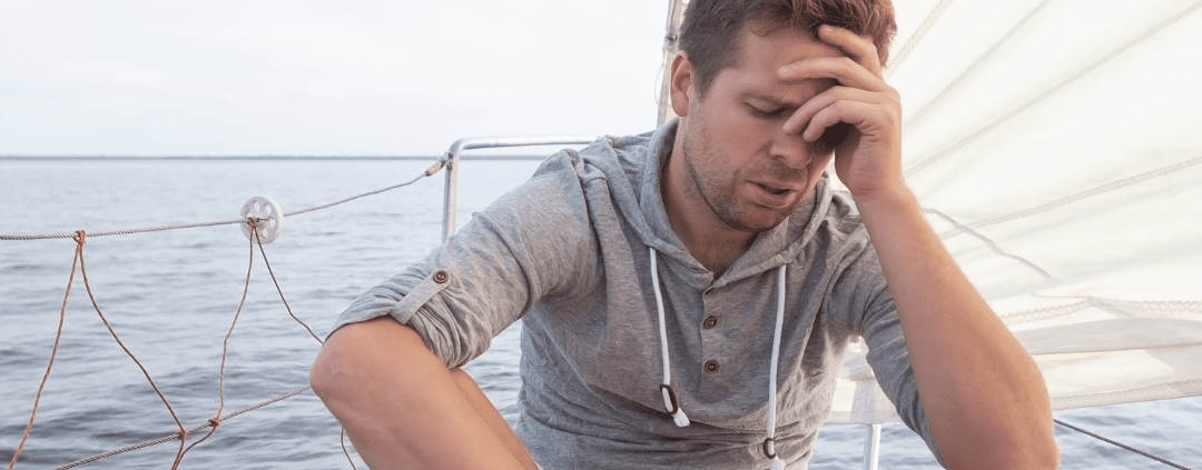 Man sitting on sailboat, looking stressed.