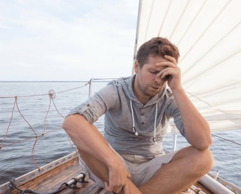 Man sitting on sailboat, looking stressed.