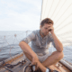 Man sitting on sailboat, looking stressed.