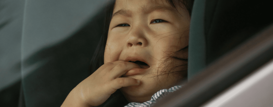 Crying child in car seat, looking outside.