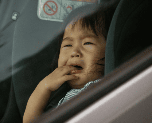 Crying child in car seat, looking outside.