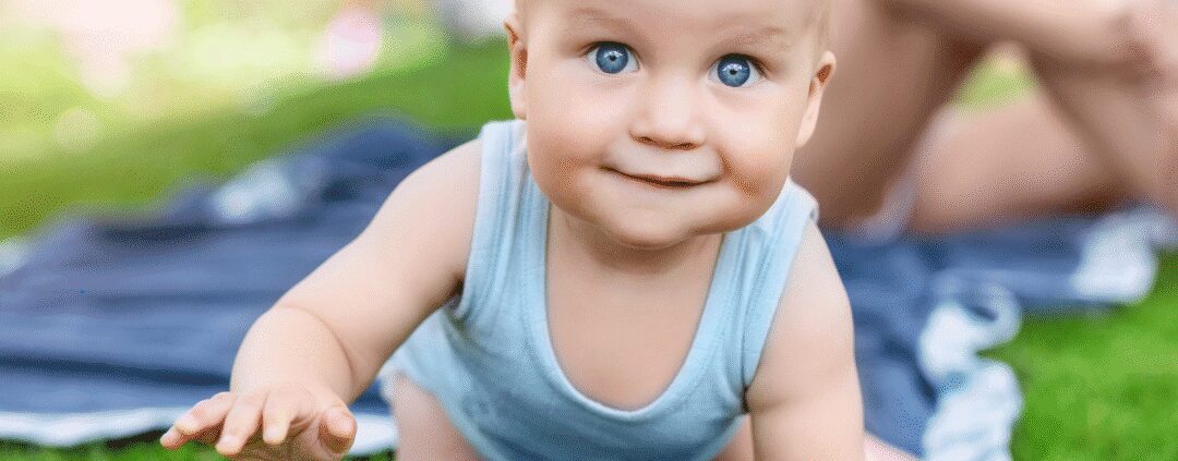 Baby crawling on grass in a garden.