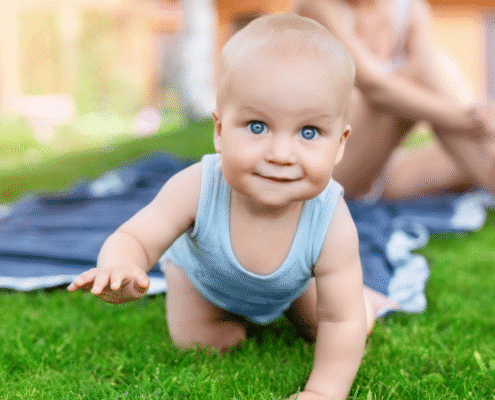 Baby crawling on grass in a garden.