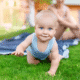 Baby crawling on grass in a garden.