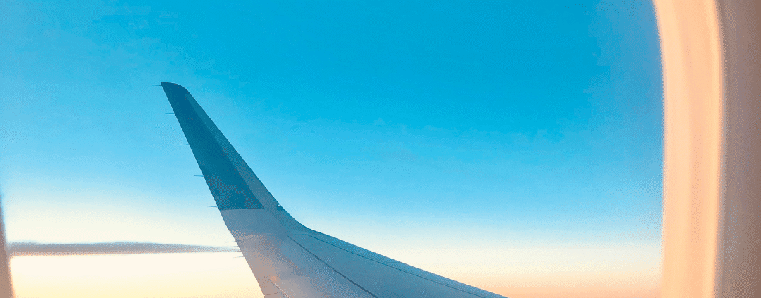 Airplane wing view at sunset from window.