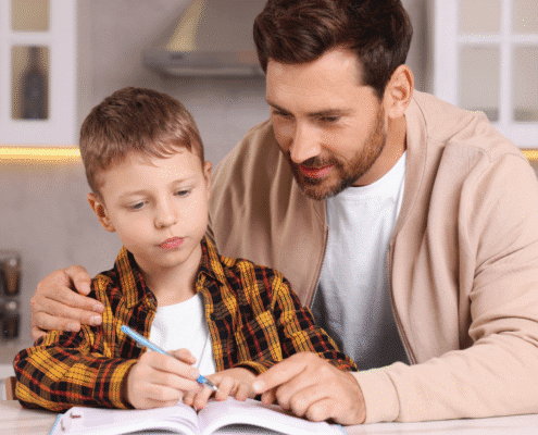 Father helping son with homework at table.