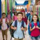 Students with backpacks walking in school hallway.