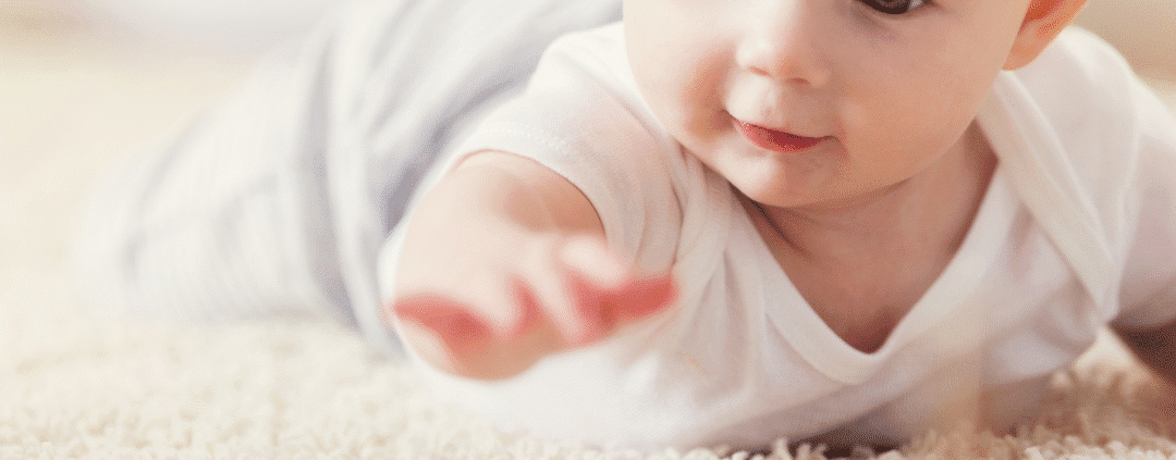Baby reaching for colorful wooden blocks.