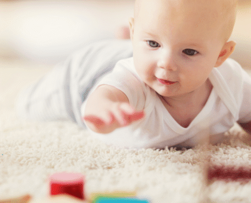 Baby reaching for colorful wooden blocks.