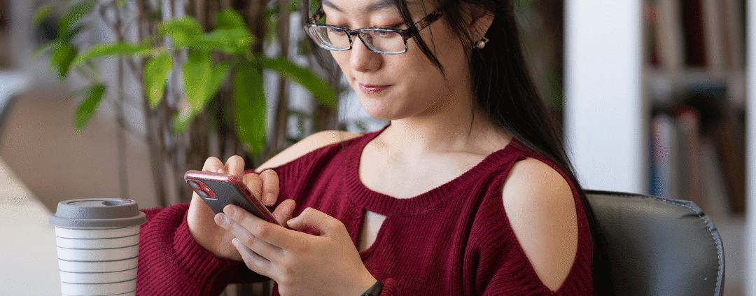 Woman using smartphone in a library.
