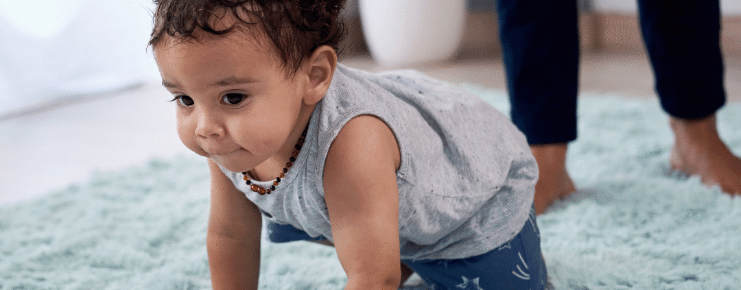 Baby crawling on soft blue carpet.