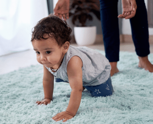 Baby crawling on soft blue carpet.