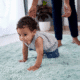 Baby crawling on soft blue carpet.