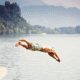 Person diving into a lake, mountains background.