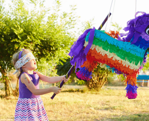 Child hitting colorful piñata outdoors.