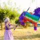 Child hitting colorful piñata outdoors.