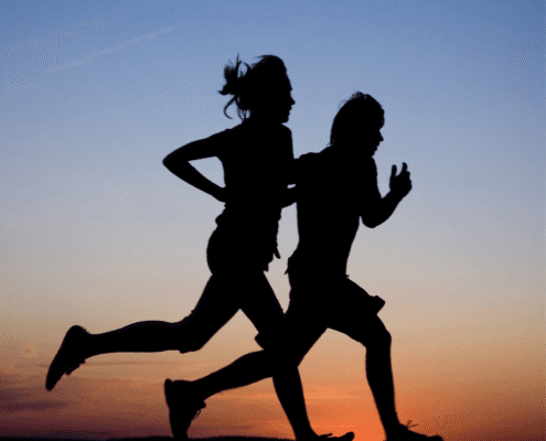 Silhouettes of two people running at sunset.
