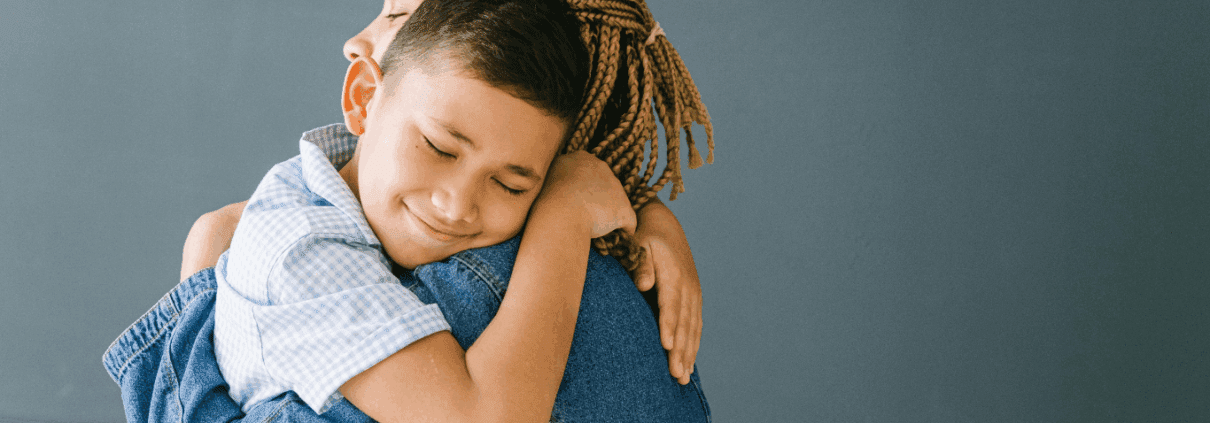 Child hugging adult, both smiling warmly.