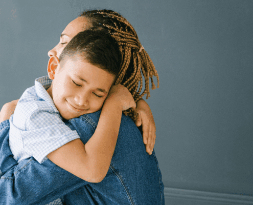 Child hugging adult, both smiling warmly.