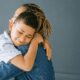 Child hugging adult, both smiling warmly.