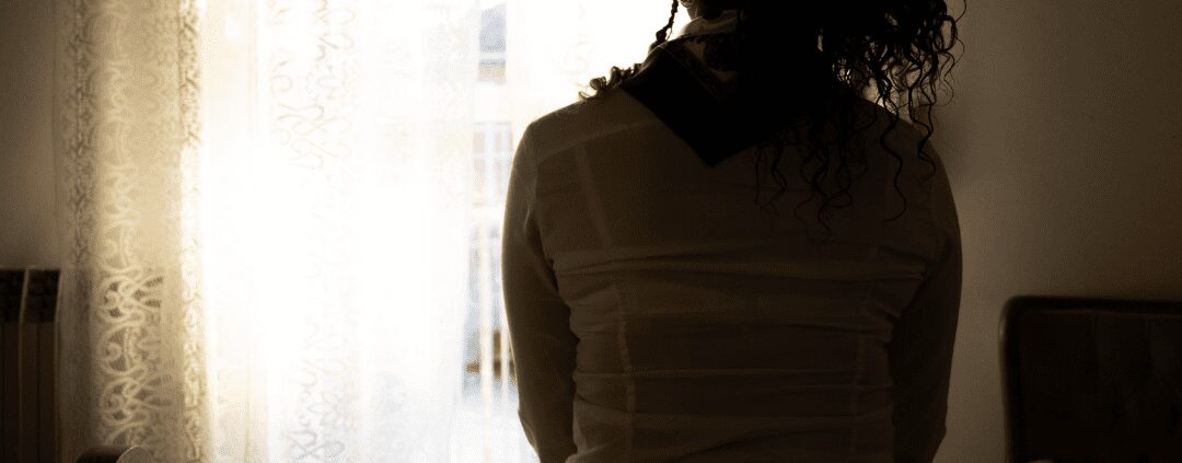 Silhouette of woman sitting by window.