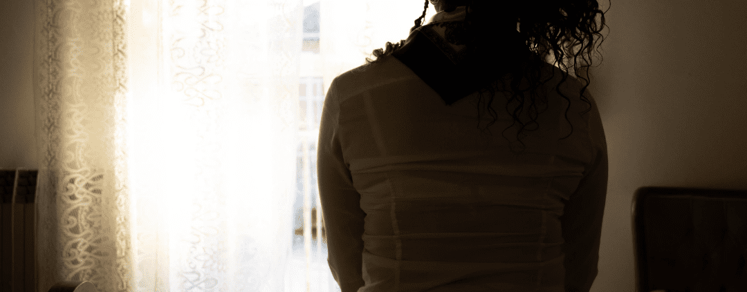 Silhouette of woman sitting by window.