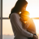 Mother and child embracing by window sunset.